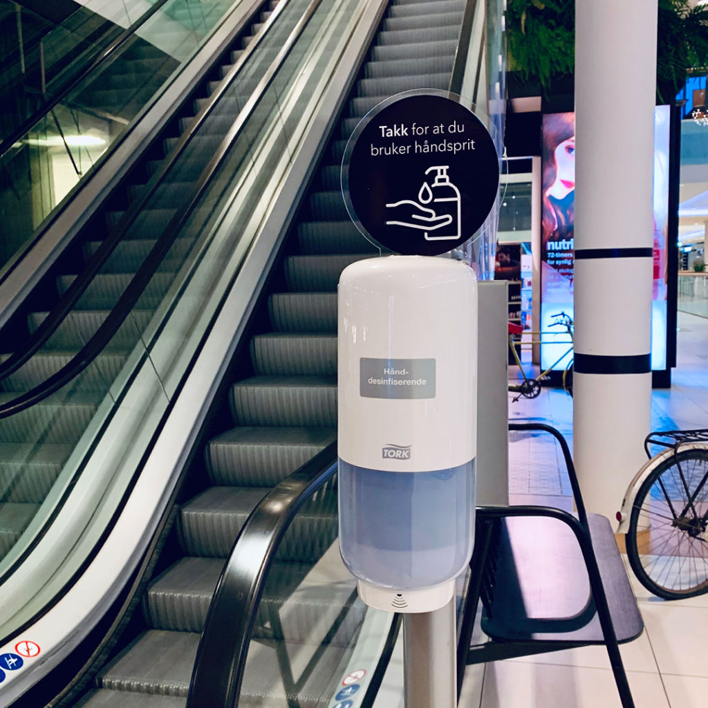 Bilde av håndspritautomat plassert ved rulletrapp